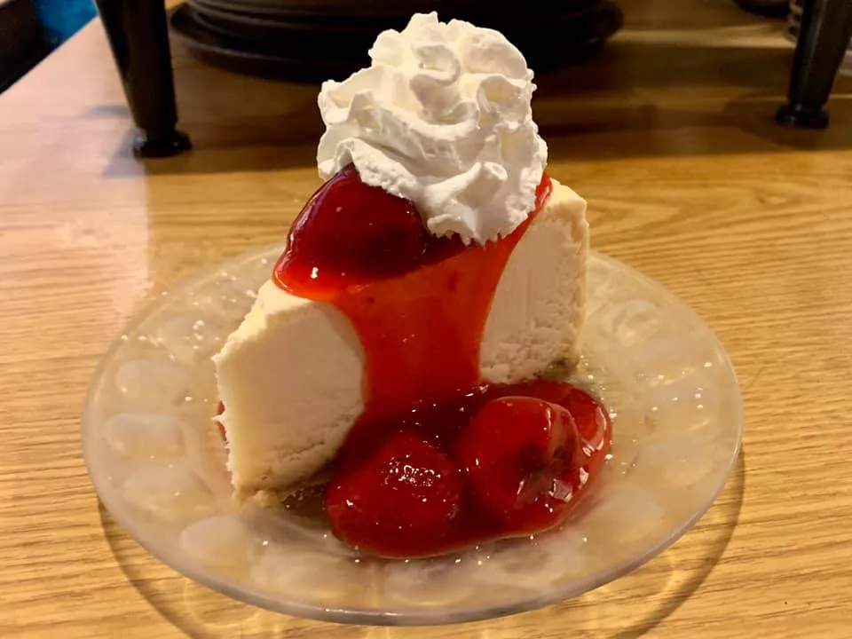 Cheesecake Topped with Whipped Cream and Either Strawberries or Blueberry Glaze